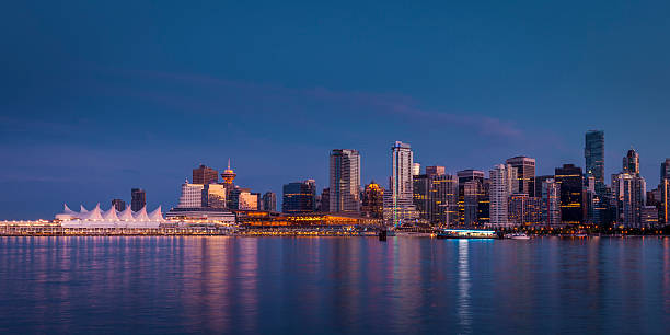 Vancouver city skyline after sunset. Vancouver office and residential buildings reflecting in water at dusk. vancouver at night stock pictures, royalty-free photos & images