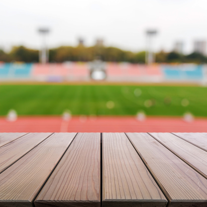 Wood table top on blur background of football field in stadium on daylight. use for sport background.