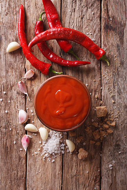 istock Red chilli sauce Sriracha with ingredients. vertical top view 636684398