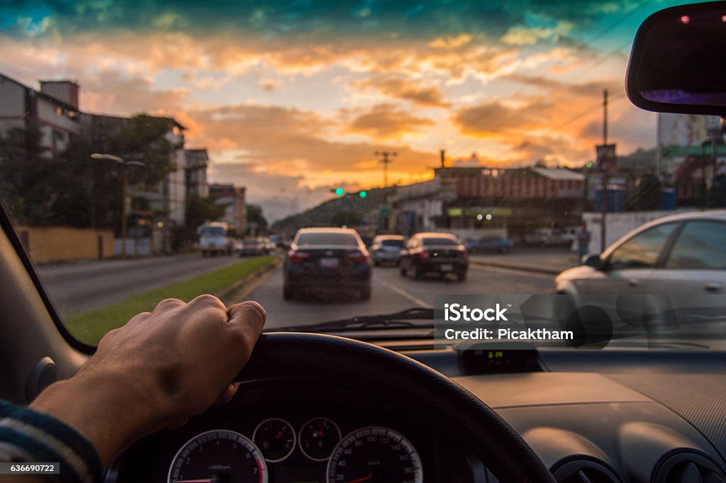 Guidare al tramonto. Vista dall'angolazione del conducente, messa a fuoco dell'auto all'interno - Foto stock royalty-free di Automobile