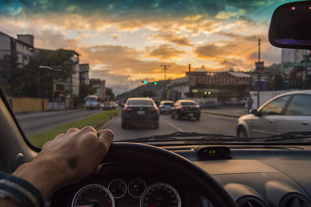 вождение на закате. вид с угла водителя, автомобиль фокусиров�ки - street cityscape city street sunset стоковые фото и изображения