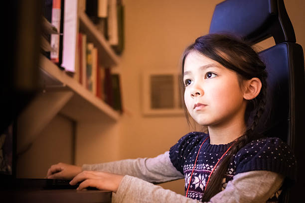 istock Focused little girl using a computer at home 636692638