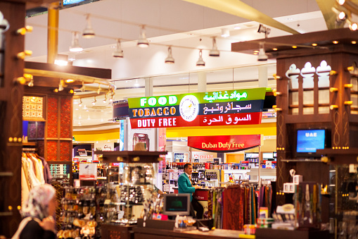 Dubai, United Arab Emirates - September 14, 2016: View into duty free food and tabacco store in airport Dubai. Capture is taking from hall. A man and staff is in background.
