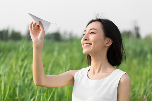 girl standing outdoors ,reeds, holding a model airplane, a symbol of the dream, wish