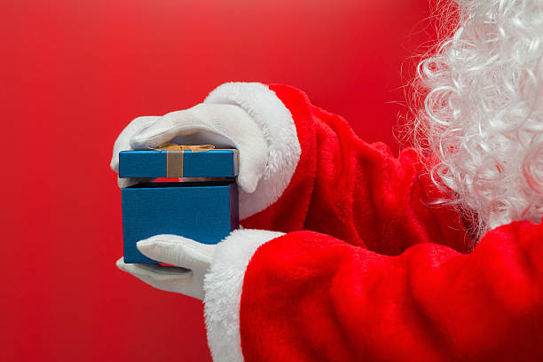 istock Santa Claus hand holding Christmas Gift box over red background 636701852