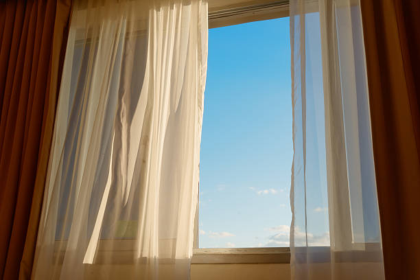 istock sunset behind curtain - open window view to sunset 636702962