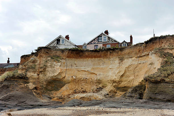 Erosion Homes on the cliff edge at Happisburgh in Norfolk demonstrating levels of erosion along the East Coast. eroded stock pictures, royalty-free photos & images
