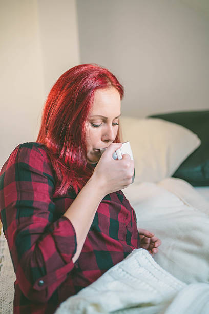 istock Attractive woman drinking tea sitting on her bed 636711560