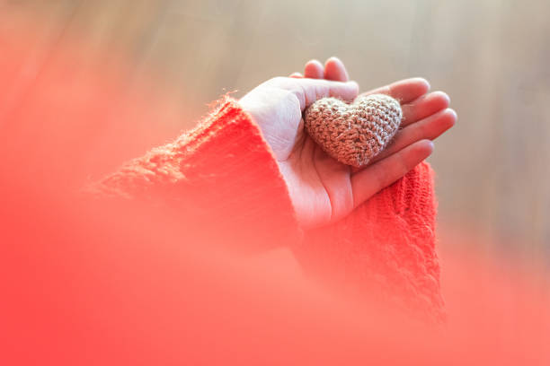 istock Woman in red jacket holding a small knitting heart on 636717506