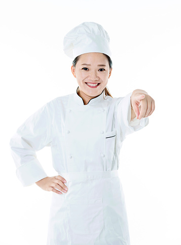 Young female chef pointing a finger against white background.