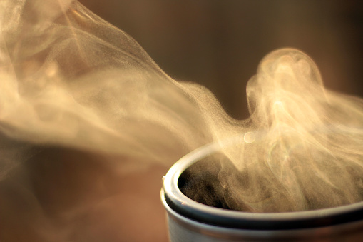 Steam of hot tea in a close-up against the sunlight; Copy space; Shallow depth of field
