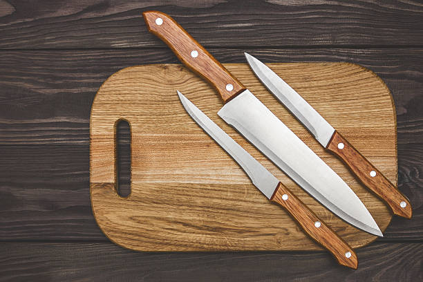 istock cutting board on wooden background with knifes 636726240