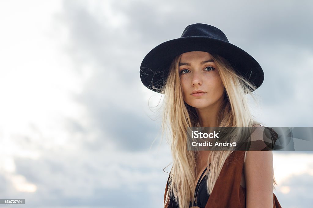 Beautiful young woman with black hat Close up of beautiful young blonde woman with black hat. Wearing brown vest. Her long messy hair looks amazing. Women Stock Photo