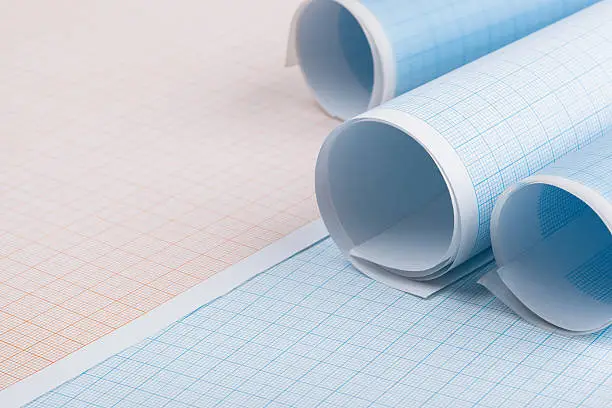 Rolls of blue graph paper on sheets of graph paper.