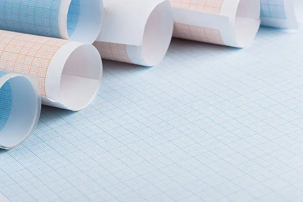 Rolls of blue and orange graph paper on sheets of graph paper.
