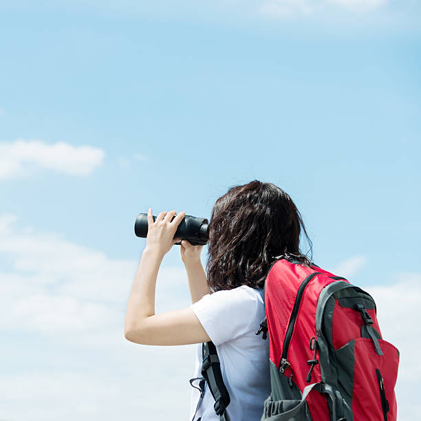 istock Female hiker looking through binoculars on top 636734328