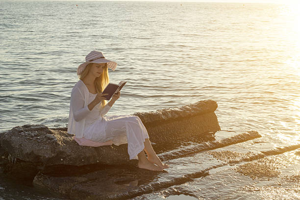 istock Leisure moment on beach, woman with hat reading a book 636741652