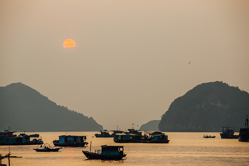 Asian fishing boats at sunset on a background of mountains. Ssunset.