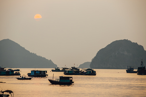 Asian fishing boats at sunset on a background of mountains. Ssunset.