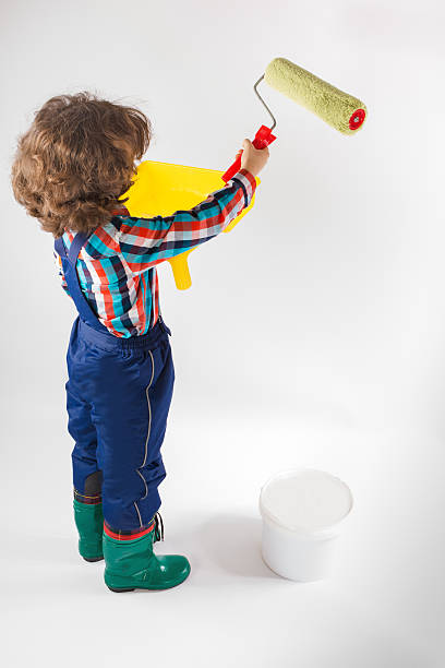 istock Cute curly painter paints the wall paint roller. Gray background. 636743516