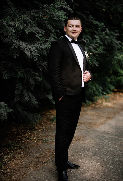 istock wedding day. Groom is staying and waking wearing black classic 636747430