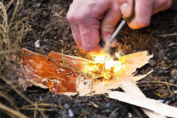 Male hand starts fire with magnesium fire steel, fire striker stock photo