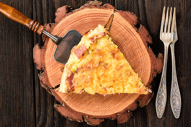 Homemade quiche with leek, ham and cheese on wooden background. stock photo