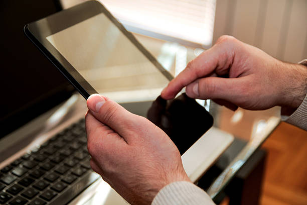 Human hands holding a tablet and using at home Human hands holding a tablet and using or online social network at home office. Business man use contact information from tablet. hanging mobile stock pictures, royalty-free photos & images