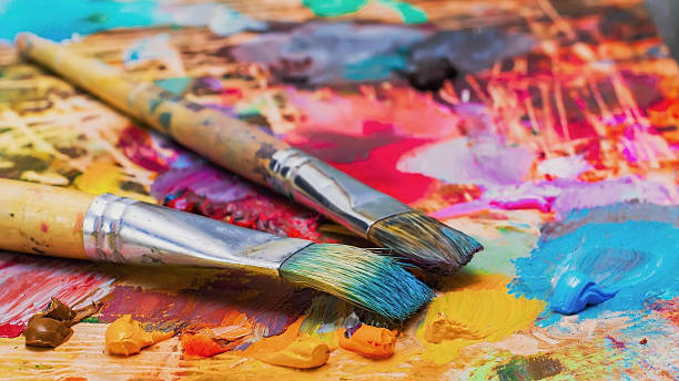 used brushes on an artist's palette of colorful oil paint - kunst stockfoto's en -beelden