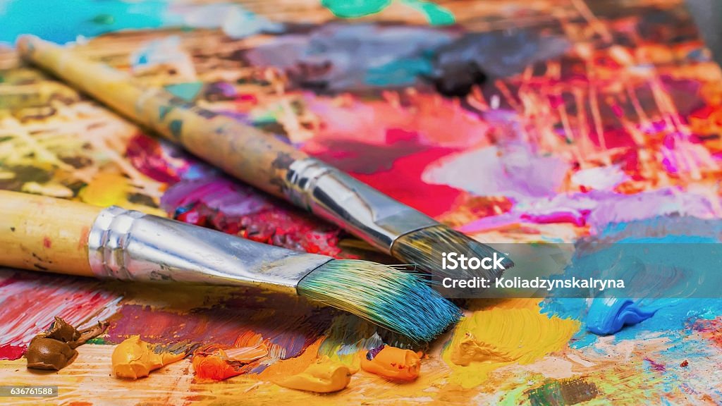 Used brushes on an artist's palette of colorful oil paint Used brushes on an artist's palette of colorful oil paint for drawing and painting Art Stock Photo