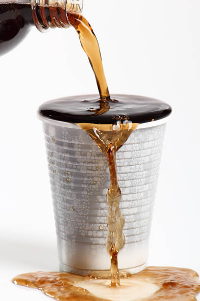 istock Pouring cola from plastic bottle into overflowing disposable cup 636776068