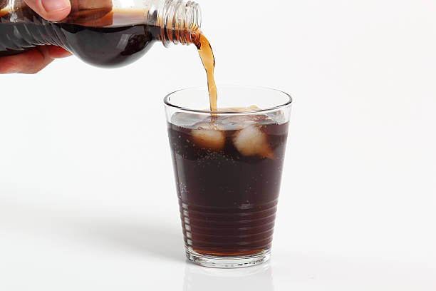 istock Pouring cola from plastic bottle into glass with ice cubes 636776138
