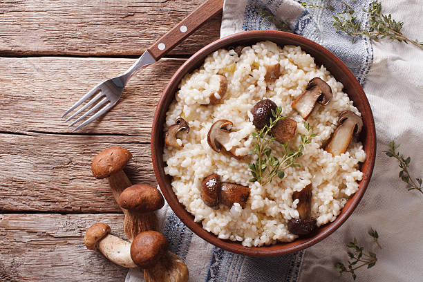 risotto with porcini mushrooms and thyme close-up. horizontal risotto with porcini mushrooms and thyme close-up on the plate on the table. horizontal view from above porcini mushroom stock pictures, royalty-free photos & images