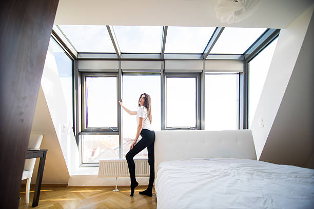 istock Woman standing near the window while stretching near bed 636782030