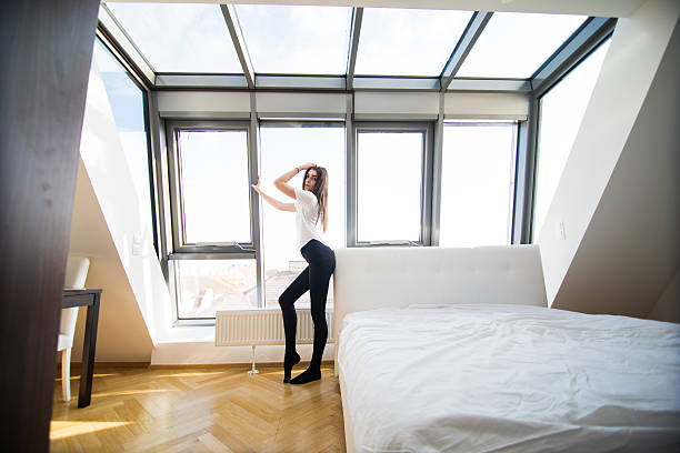 istock Woman standing near the window while stretching near bed 636782076