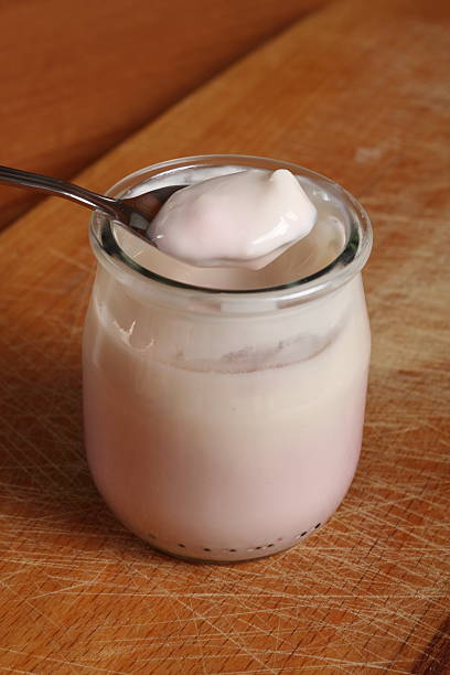 istock Spoon with yogurt on open small glass jar 636782592