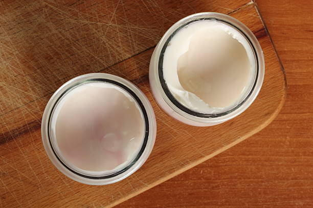 istock Yogurt in open small glass jar on wooden cutting board 636782720