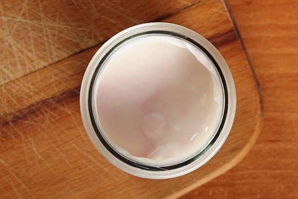 istock Yogurt in open small glass jar on wooden cutting board 636782736