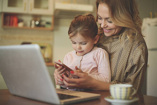 mère avec fille utilisant un téléphone portable. - typing busy business women photos et images de collection