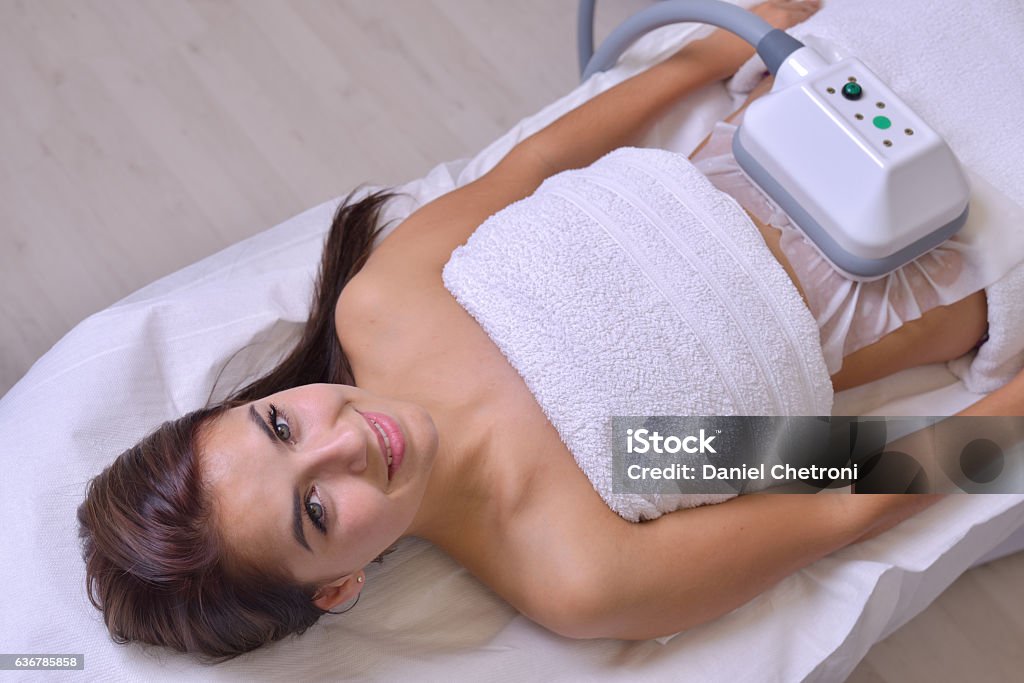 Beautiful young woman getting cryolipolyse treatment in cosmetic cabinet Beautiful young woman getting cryolipolyse treatment in cosmetic cabinet. Cryolipolyse Overweight Stock Photo