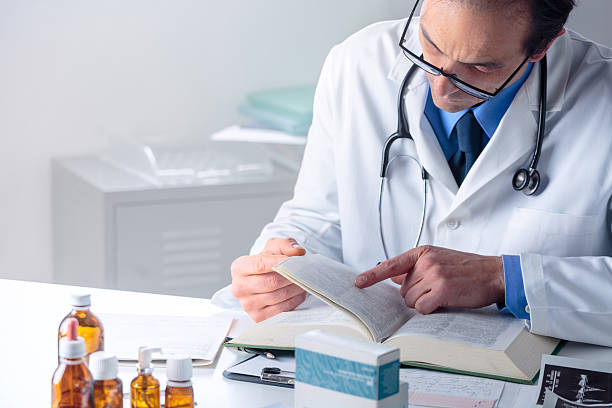 医学書で情報を探してい��る上級男性医師 - pill bottle pill stethoscope medical exam ストックフォトと画像