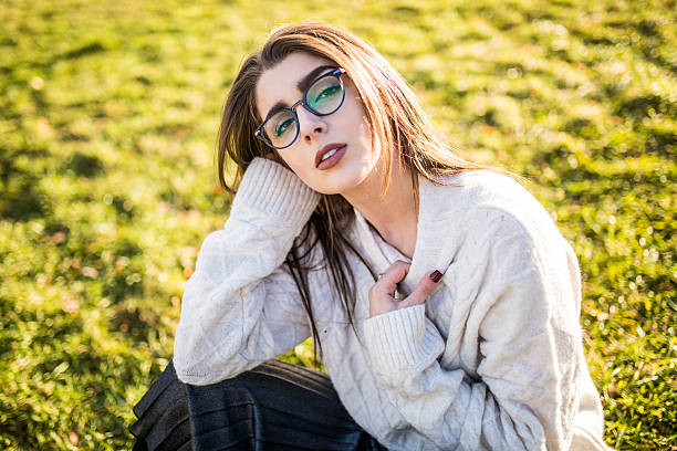 istock Young Woman sitting on grass in park on sunny day 636793966