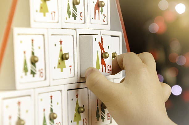 Wooden advent calendar Christmas tree and child Child's hand pulling the last drawer (number 24) of a wooden advent calendar Christmas tree. advent photos stock pictures, royalty-free photos & images