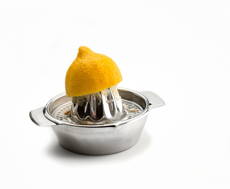 Kitchen Utensils: Citrus Squeezer, chrome citrus juicer with  one ripe yellow lemon pressed on the squeezer ,isolated on white. High angle view.