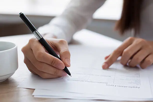 Photo of Closeup of Woman Completing Application Form