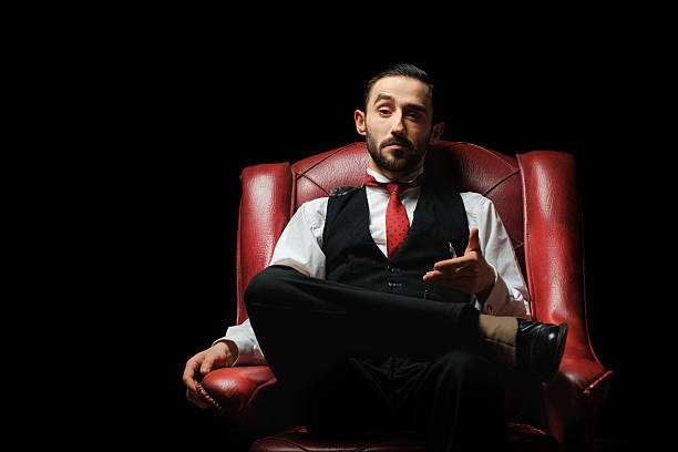 side view of an elegant young businessman smoking a cigarette on black studio background Close up