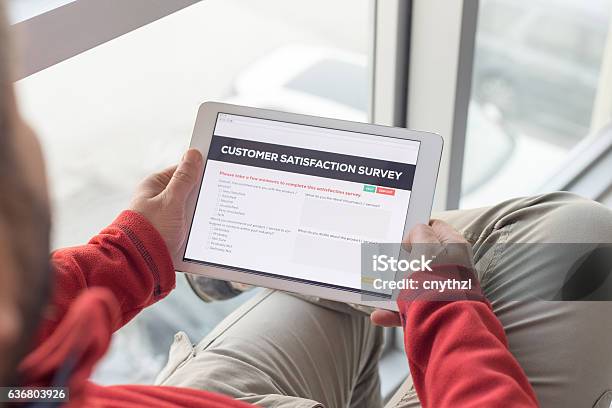 Man Working On Tablet With Customer Satisfaction Survey On Screen Stock Photo - Download Image Now