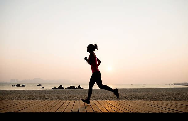 istock Woman jogging on shore at sunrise 636804880