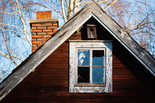 Broken window and birdhouse on old house