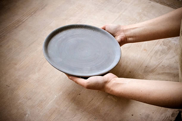istock Person holding an empty plate on a wooden table 636805856